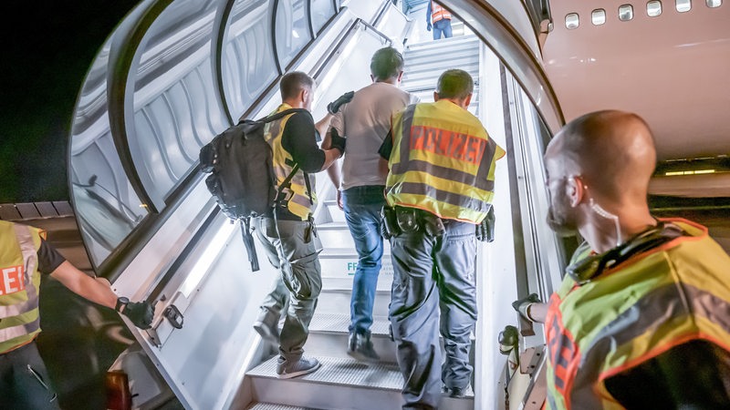 Polizeibeamte begleiten einen Afghanen auf dem Flughafen Leipzig-Halle in ein Charterflugzeug. (Archivbild)