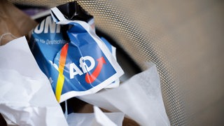 Ein Flyer der AfD liegt zerknüllt in einem Mülleimer.