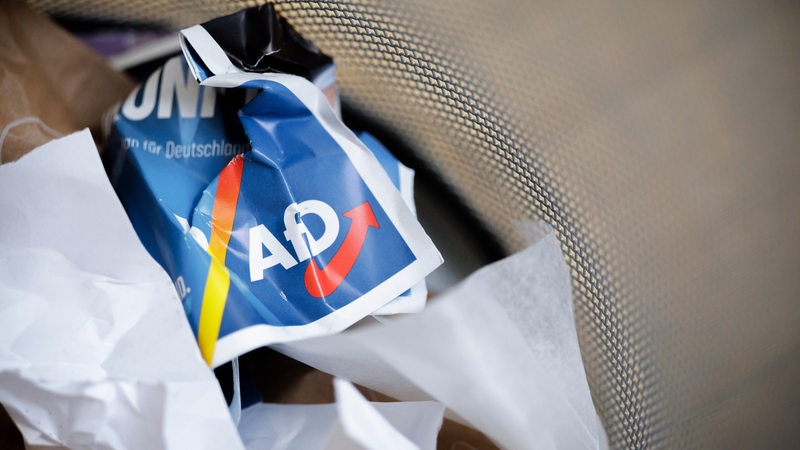 Ein Flyer der AfD liegt zerknüllt in einem Mülleimer.