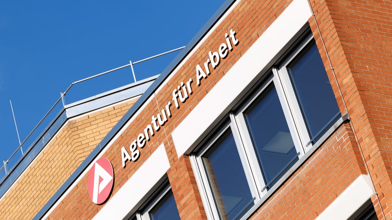 Das Logo der Agentur für Arbeit hängt an einem Gebäude.