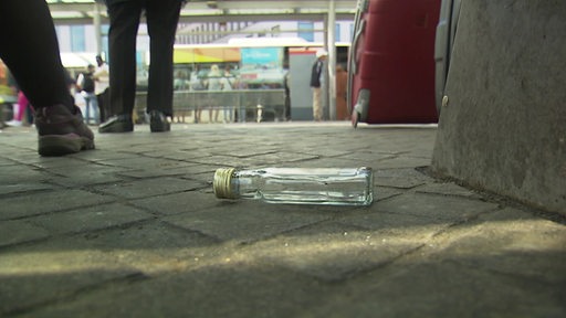 Eine Flasche Alkohol liegt unter einer öffentlichen Sitzbank in der Bremer Innenstadt.