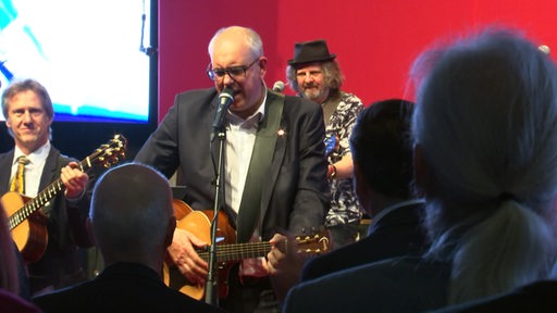 Der SPD-Spitzenkandidat Andreas Bovenschulte mit Gitarre auf der Bühne.