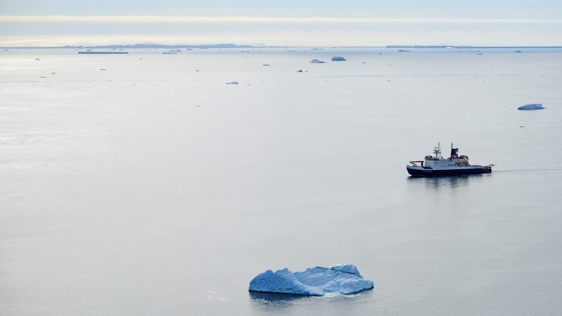 Ein Schiff fährt übers Meer mit nur wenigen Eisschollen.