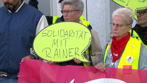 Demonstranten halten ein Schild auf dem "Solidarität mit Rainer" steht.