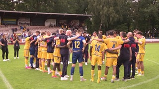 Die Spieler und Trainer von Atlas Delmenhorst bilden einen Mannschaftskreis.