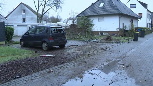 Ein Auto steht auf einem Grundstück in einer Wohnsiedlung. 