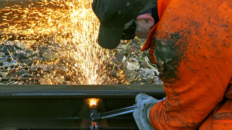 Arbeiter mit Schweißgerät an einer Schiene