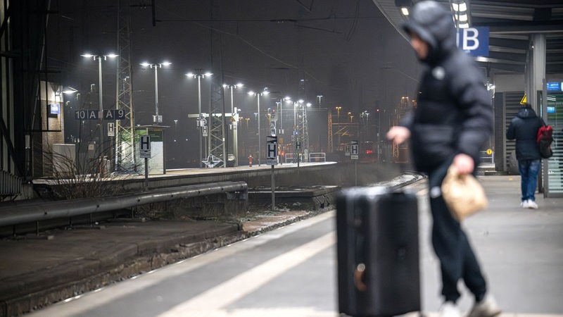 Ein Mann steht auf einem leeren Bahnsteig.