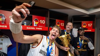 Moritz Wagner, Daniel Theis und Dennis Schröder bejubeln den Gewinn des WM-Pokals.