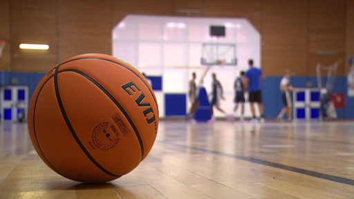 Im Vordergrund ein Basketball und im Hintergrund trainieren die Eisbären.