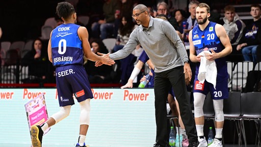 Basketball-Coach Steven Key von den Eisbären Bremerhaven klatscht am Spielfeldrand mit Aaron Cook ab, der das Parkett verlässt.