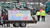 Mit Traktoren und einem Transparent mit der Aufschrift: "Es geht und alle an" demonstrieren ein Landwirte mit Traktoren