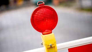 Eine rote Warnleuchte hängt an einer Absperrung vor einer Baustelle.