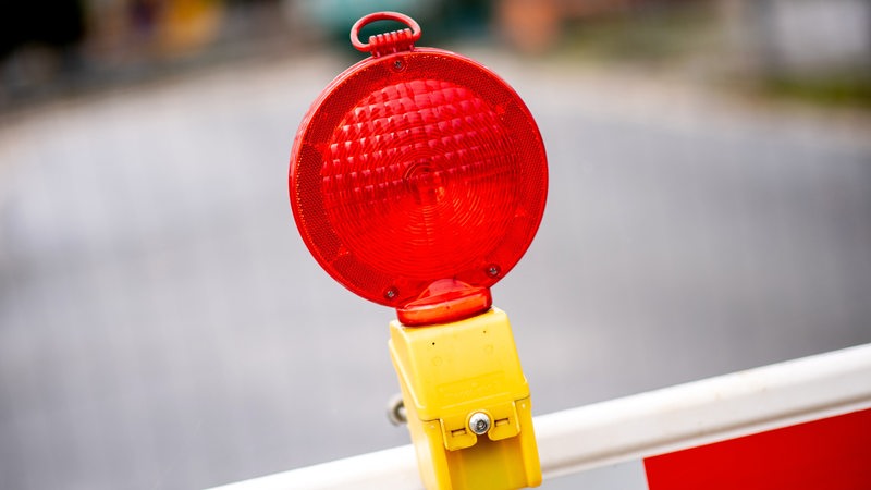 Eine rote Warnleuchte hängt an einer Absperrung vor einer Baustelle.