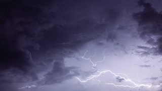 Ein Blitz zieht sich über einen dunklen, wolkenverhangenen Himmel.