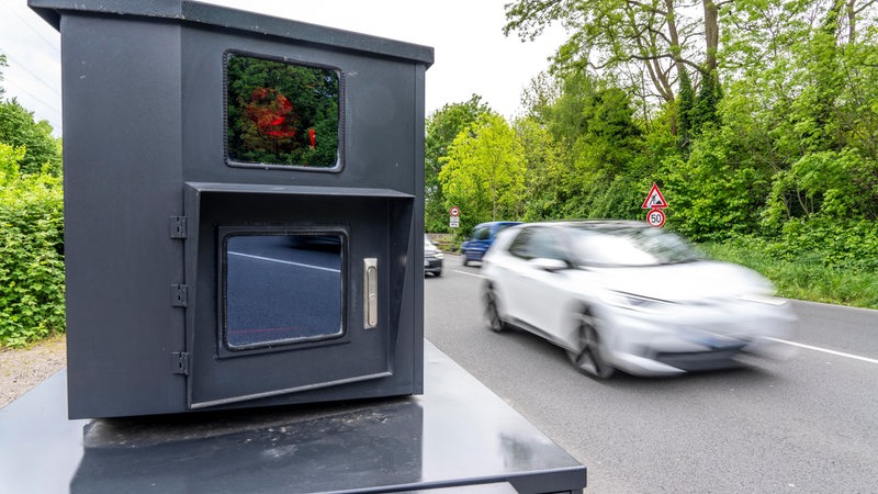 Mobiler Blitzer steht auf einer Landstraße, Auto fährt vorbei