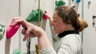 Eine Frau bouldert in einer Boulderhalle.