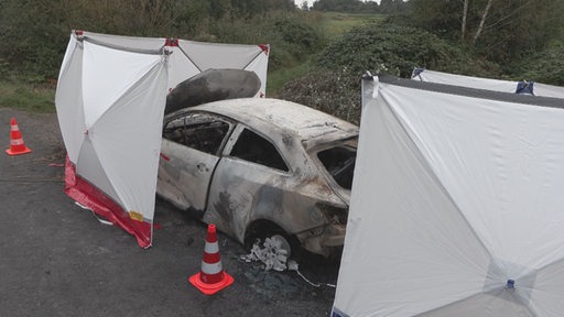 Ausgebranntes Auto mit Sichtschutz