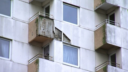 Blick von der Straße auf mehrere beschädigte Hochhaus-Balkone.