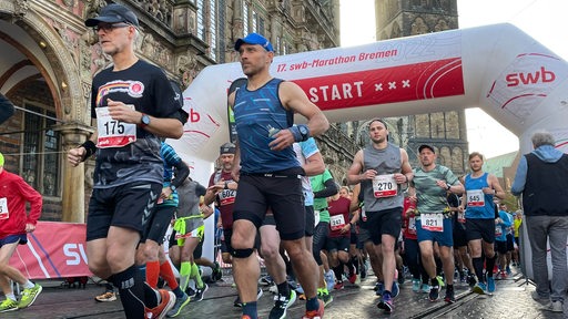 Beim Bremen Marathon passieren mehrere Läufer die Startlinie.