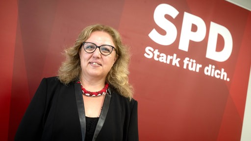 Özlem Ünsal posiert vor einem SPD-Wappen.