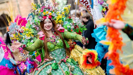 Eine Frau im bunten Kostüm zieht strahlend mit beim Straßenumzug zum 40. Bremer Samba-Karneval durch die Innenstadt unter dem Motto "Uns blüht was". 