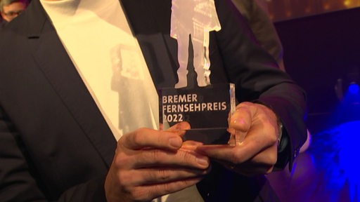 Der Bremer Fernsehpreis in den Händen eines Mannes.