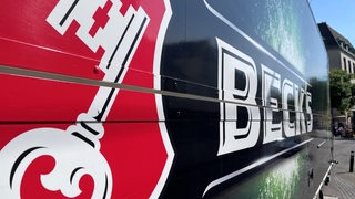 Seitenansicht eines LKW der Firma "Beck's" mit dem einem Schlüssel im Vordergrund.