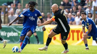 Ein Spieler des Bremer SV dribbelt mit dem Ball an seinem Gegenspieler von der SV Hemelingen vorbei.