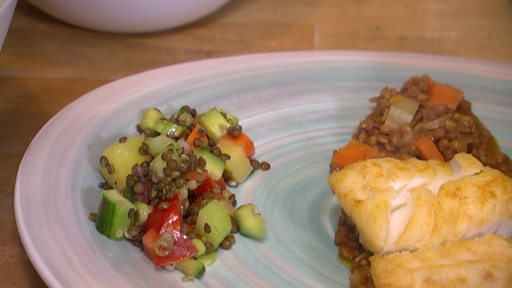 Auf dem Bremer Teller ist ein Linsensalat mit Gurke, Paprika und Möhren platzierzt. Zudem ist ein Kabeljaufilet auf gekochten Linsen zu sehen. 