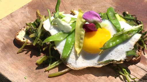 Ein Brot mit Spiegelei und Bohnen auf einem Frühstücksbrett