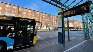 Ein Bus steht vor einer leuchtenden Anzeigetafel.