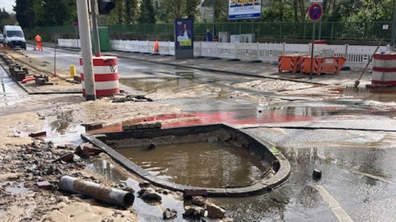 Auf einer verwüsteten Straße in einer Baustelle sind Steine und Pfützen zu sehen.