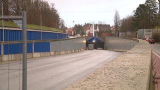 Eine abgesperrte, leere Straße führt in einen Tunnel.