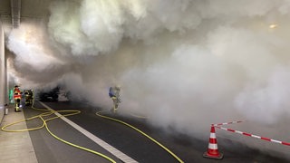 Feuerwehrleute stehen in großen Rauchschwaden im Bremerhavener Hafentunnel.