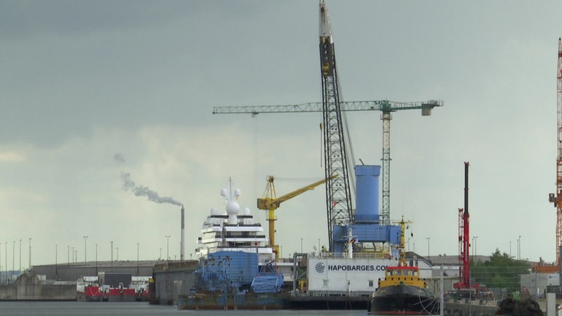 Ein Kran ragt neben einem Schiff in den Himmel.