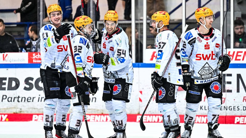 Mehrere Eishockeyspieler stehen auf dem Spielfeld.