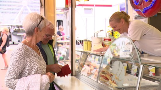 Ein Ehepaar steht an einer Fischbude bei den Maritimen Tagen und werden bedient.