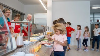 Kinder stehen am Buffet und nehmen sich Frühstück