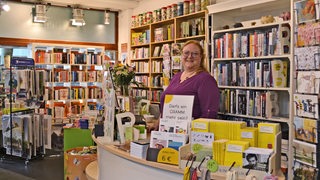 Eine Frau steht hinter einer Theke in einem Buchladen.