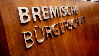 Auf einem Holzpult steht der Schriftzug "Bremische Bürgerschaft".