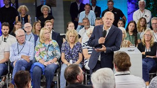 Bundeskanzler Olaf Scholz steht während eines Bürgerdialogs an einem Rednerpult.