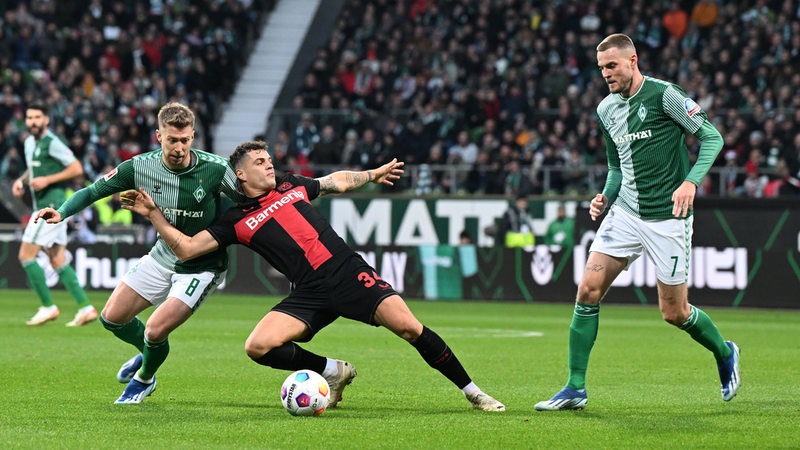  Werders Romano Schmid (links) und Marvin Ducksch (rechts) kämpfen mit Leverkusens Granit Xhaka um den Ball. 