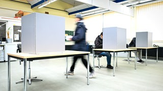 Eine Person geht in eine Wahlkabine bei der Bundestagswahl in Bremen.