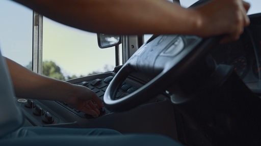 Ein Busfahrer von unten im Cockpit