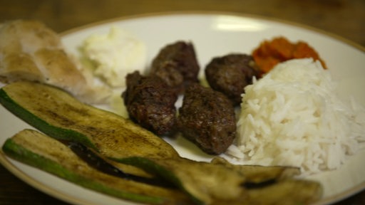 Auf dem Bremer Teller sind bosnische Cevapcici, Reis, Salat und gegrillte Zucchini zu sehen.