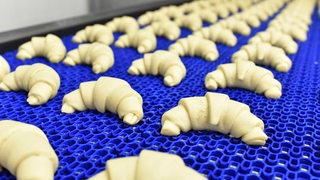 Viele Croissants liegen auf einem blauen Band.