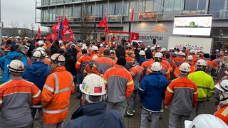 Viele Menschen stehen vor einem Gebäude.