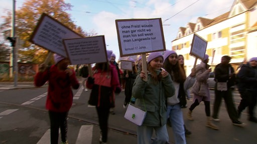 Viele Kindern halten bei einem Streik Schildern in die Luft.