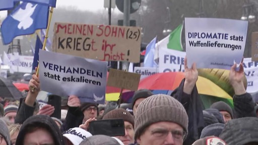 Viele Personen halten bei einer Demonstration Schilder gegen Waffenlieferungen an die Ukraine hoch.